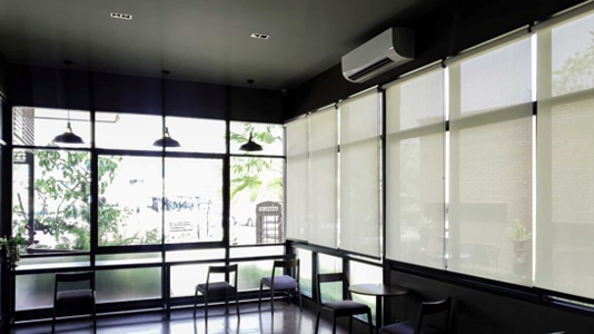 Large roller window blinds covering bay floor-to-ceiling windows