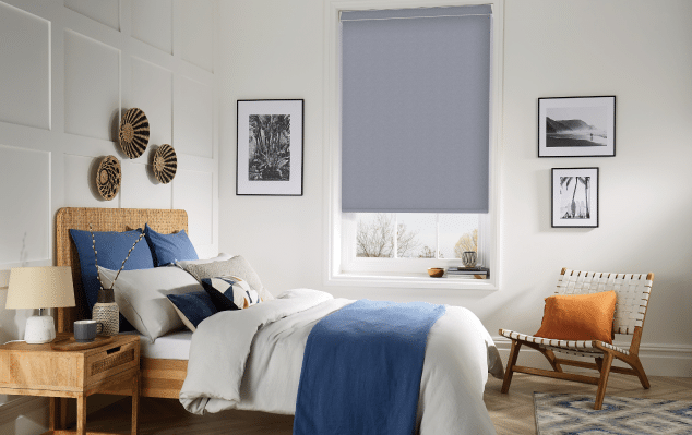 Pale grey bedroom wall showing a pale blue blackout roller blind Auckland 3/4 rolled down, from Home Vision Blinds.